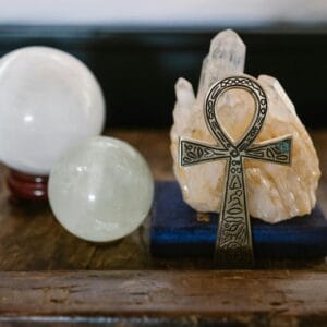 A symbolic Ankh with crystal spheres represents mystic energy on a wooden surface, ideal for spiritual themes.